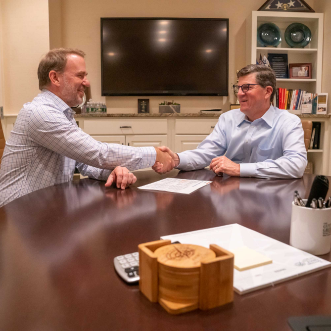 Two men shaking hands at table